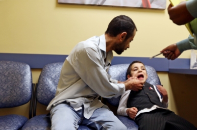 Abdul Kareem Almahdi, left, holds the mouth of his youngest son, Laith, 5, to show the dental assistant new teeth growth during an appointment on Thursday, March 30, 2017. Originally from Raqqah, Syria, the family spent four years living at a refugee camp in Jordan before being relocated to the United States. Located in the north eastern part of Syria and seized by militants in late 2013, the city the family once lived, is now the capitol of the Islamic State.