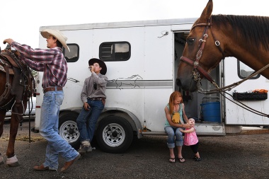 Evan Koster attends to his horse while standing next to J.D. Slagowski as Evan's wife, Maggee Koster holds their daughter, Raelyn Koster, 1, prior to the start of the Snowmass Rodeo on Wednesday July 19, 2017 in Snowmass Village, CO. This is the 44th year for the weekly rodeo that runs from mid-June through August.
