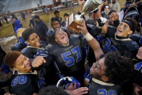 1st Place Sports: Jonathon Gruenke, Daily Press---Phoebus' Ramel Lewis, center, other players celebrate with the trophy after defeating Norcom 7-6 in triple overtime during Saturday afternoon's Class 3 Region A championship game at Darling Stadium November 24, 2018.