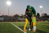HM Place Sports: Jonathon Gruenke, Daily Press---William and Mary head football coach Jimmye Laycock hugs his granddaughters Grail Johnson, left, and Nolan Johnson after the conclusion of Saturday's game against the University of Richmond at Zable Stadium November 17, 2018. Saturday concluded his 39th and final season as William and Mary's head football coach. Laycock holds the third-longest continuous head-coaching tenure in Division I football history. Ten of his teams reached the national playoffs, two advanced to the semifinals and he has coached more than 800 young men.