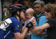 HM Place Sports: William Douglas Graham, Loudoun Now---Professional cyclist Lindsay Bayer gives her newborn a kiss as her mom looks on before starting the Armed Forces Cycling Classic bicycle race.